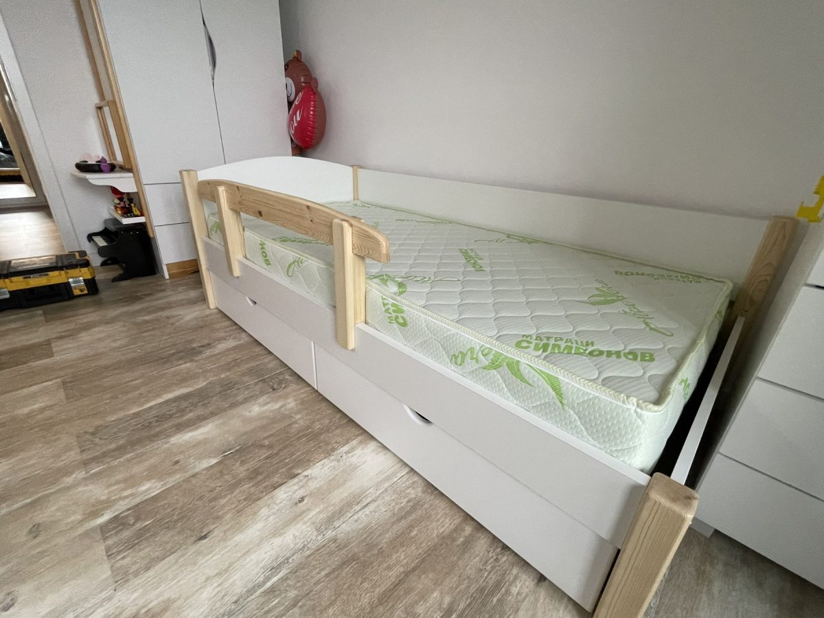 Единично детско легло от MDF, иглолистна дървесина и ПДЧ в бял и натурален дървесен цвят с две чекмеджета за допълнително съхранение и предпазна преграда – стилен и функционален дизайн за детска стая